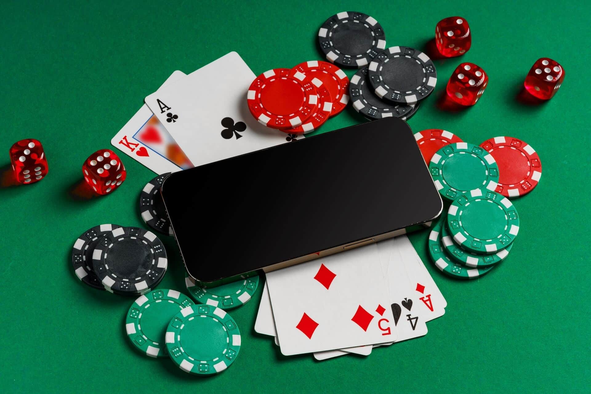 Smartphone on a casino table with poker chips, dice, and playing cards