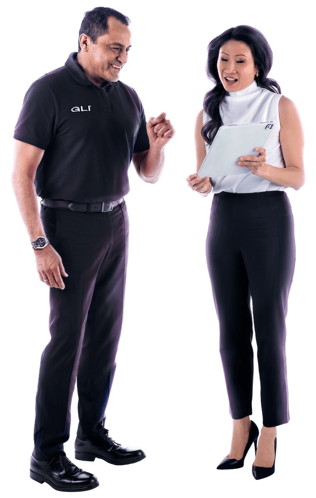 Two GLI colleagues wearing black and white business casual stand together smiling while reviewing a tablet.