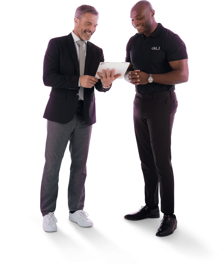 Two GLI colleagues wearing black business casual stand together smiling while reviewing a tablet.
