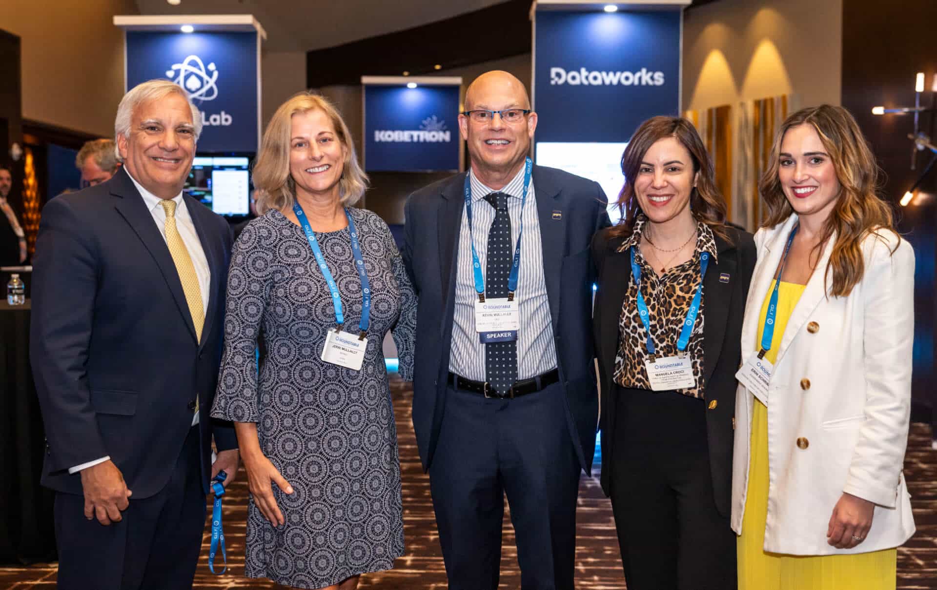 Five attendees wearing professional attire attend the GLI-backed Regulators Roundtable event, posing in a networking area.