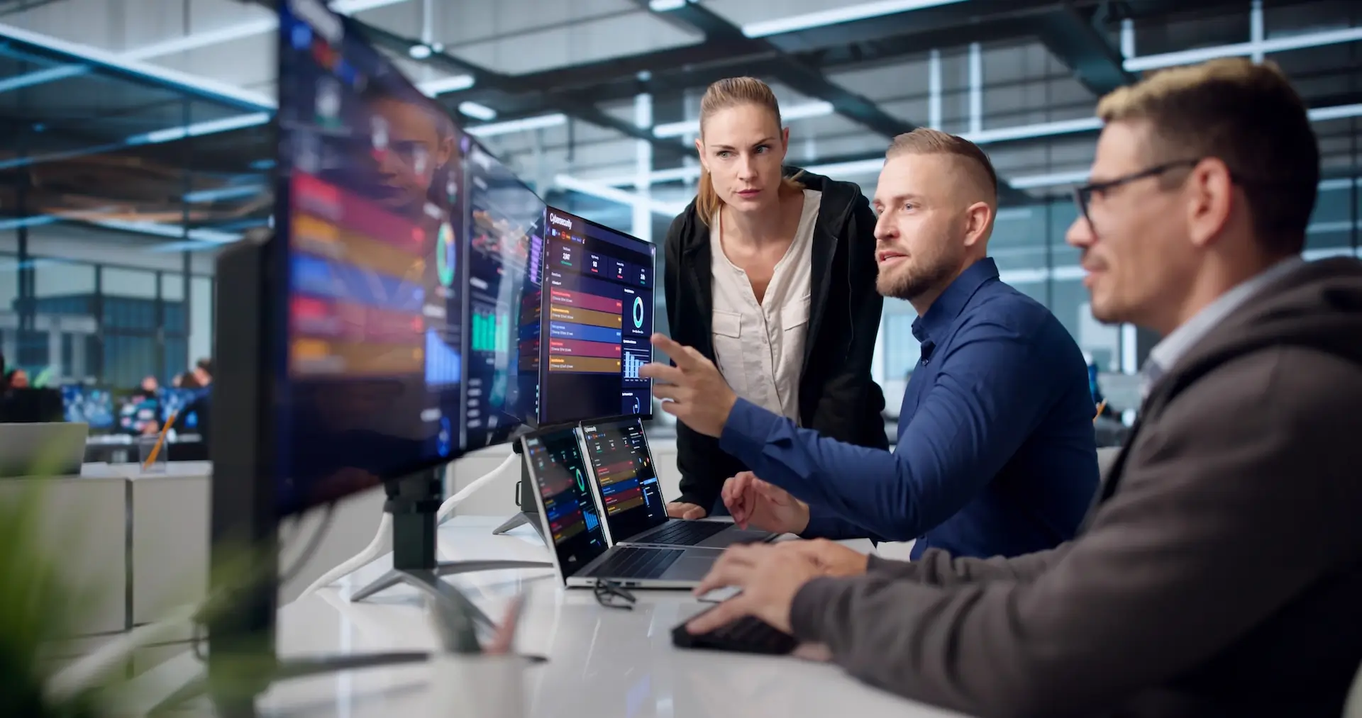 Technology professionals reviewing cybersecurity dashboards and analytics on multiple monitors in a security operations environment.